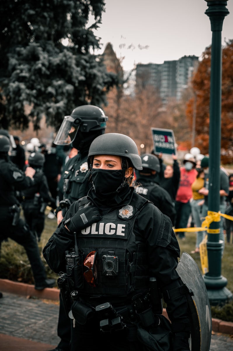 man in black helmet and black jacket standing near people during daytime