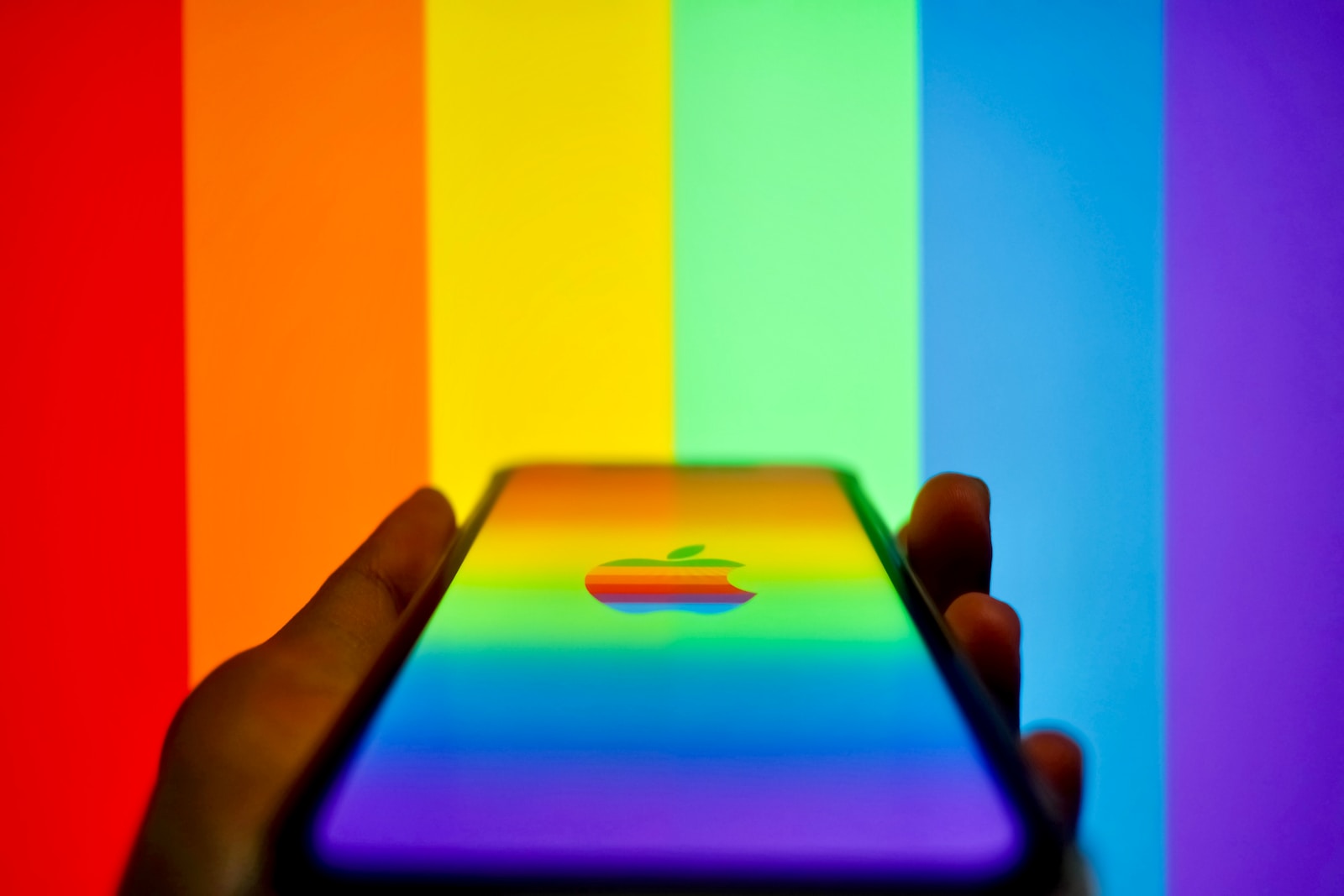a person holding an iphone in front of a rainbow background